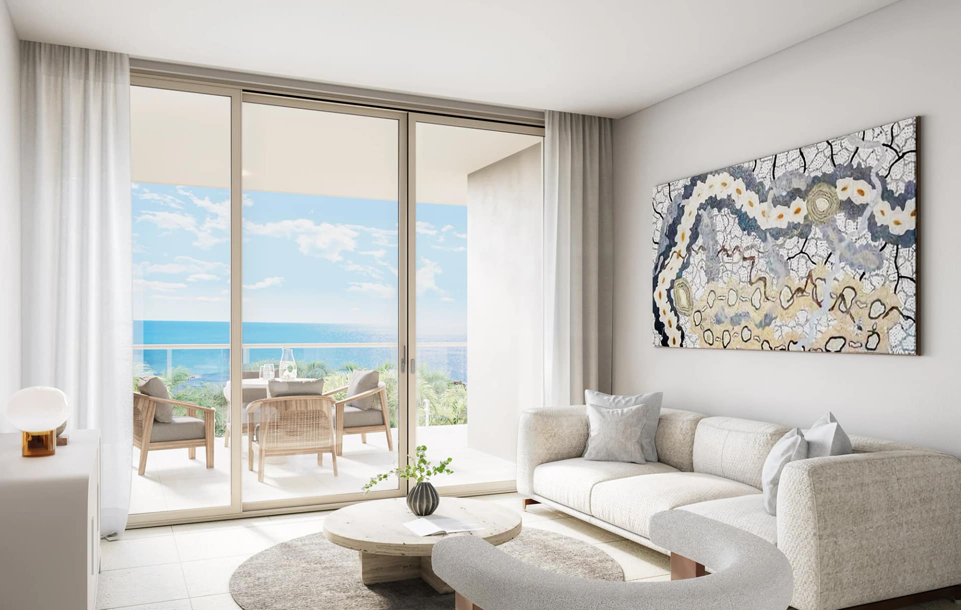 Open-plan living room opening through wide glazed doors to a balcony and the ocean beyond