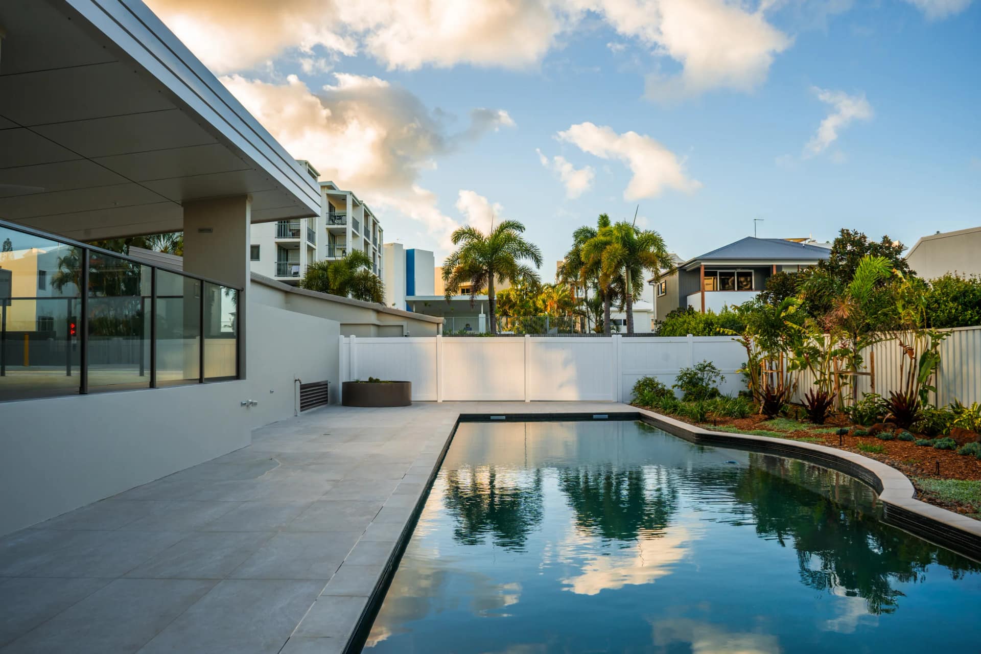 The completed resident-only pool at dusk, the covered alfresco room beside it and new planting along the fence