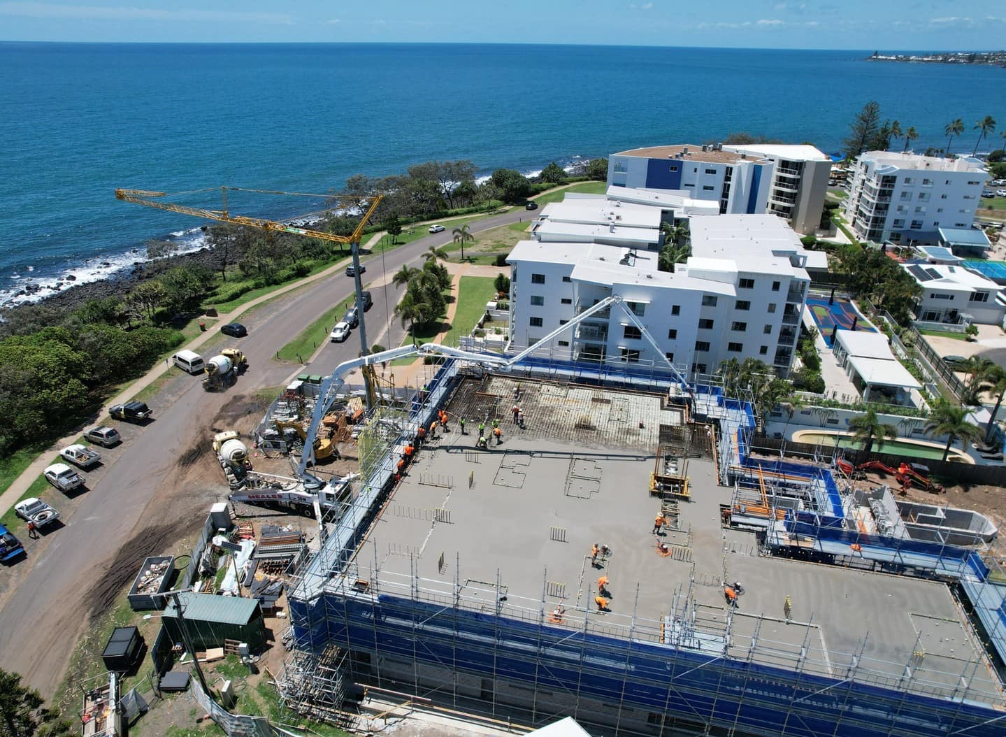 Aerial view of the building with a concrete pump reaching over a freshly poured floor, the Coral Sea beyond